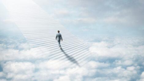 Ethereal sky with staircase and a business man walking up